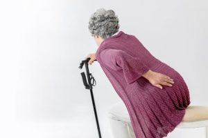 腰が痛くて杖を使う高齢女性