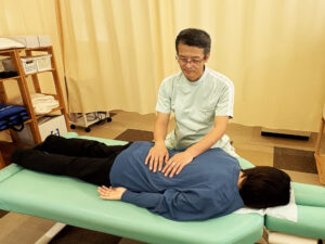 うつ伏せで背骨をやさしくゆらす施術をする院長